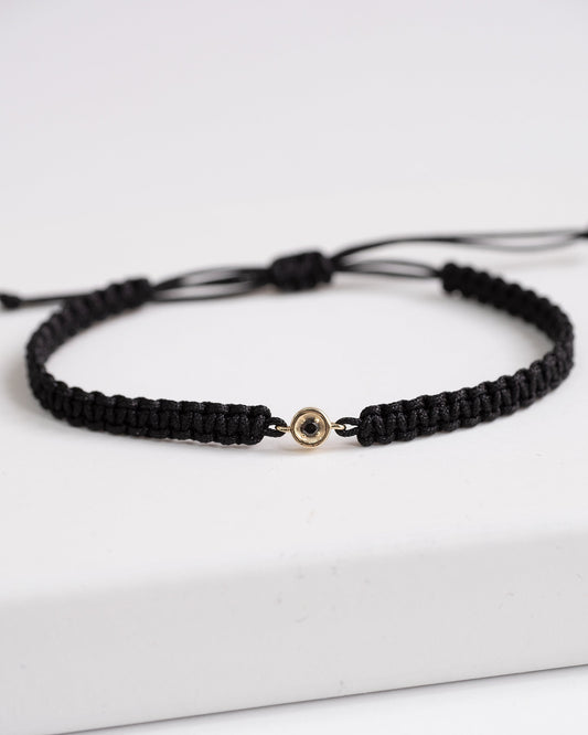 a black cord bracelet with a gold clasp