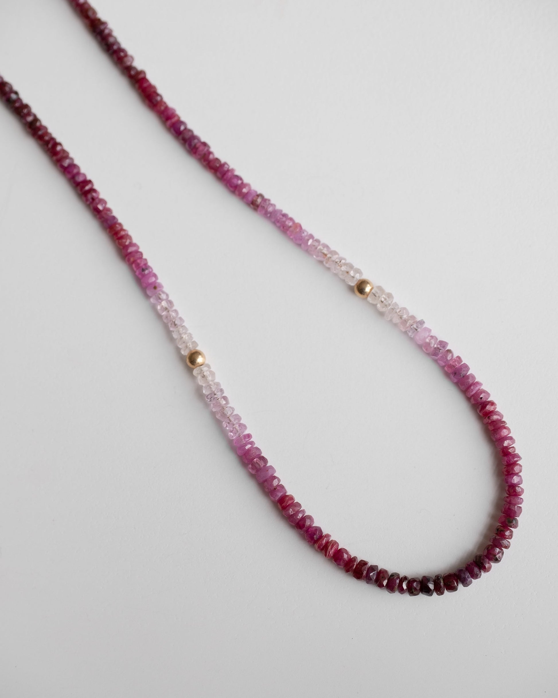 gold beaded necklace with shaded ruby gemstones and two little gold balls 