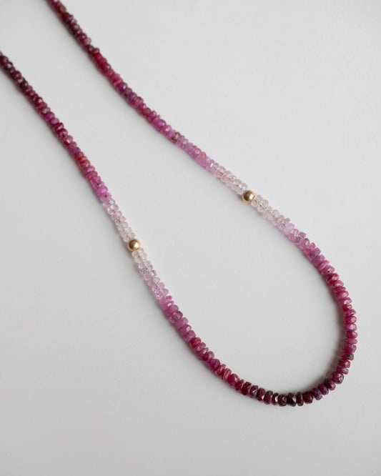 gold beaded necklace with shaded ruby gemstones and two little gold balls 